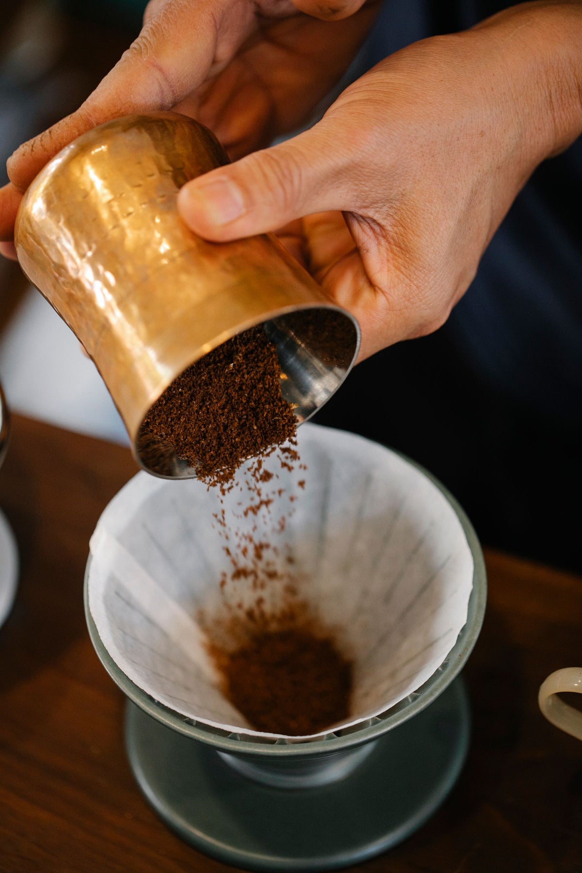 Barista pouring ground coffee into a pour-over dripper